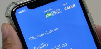 close em tela de celular com aplicativo do auxílio emergencial aberto; pessoa segura o celular