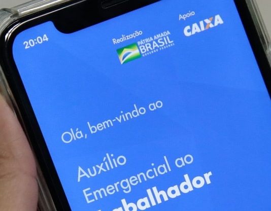 close em tela de celular com aplicativo do auxílio emergencial aberto; pessoa segura o celular