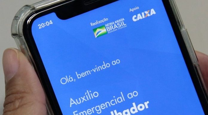 close em tela de celular com aplicativo do auxílio emergencial aberto; pessoa segura o celular