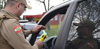 policial militar fazendo o teste de bafômetro em motorista