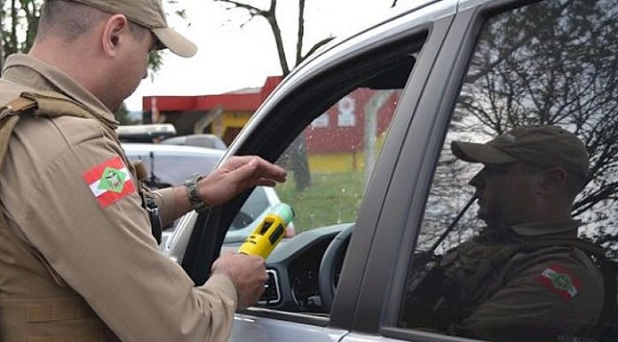 policial militar fazendo o teste de bafômetro em motorista