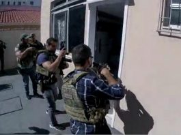 policiais armados com metralhadoras em posição de invasão na porta de uma kitnet
