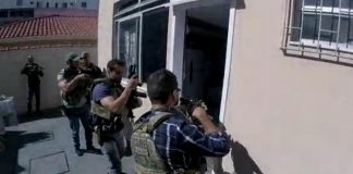 policiais armados com metralhadoras em posição de invasão na porta de uma kitnet