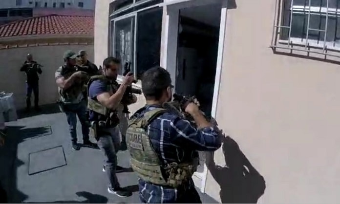 policiais armados com metralhadoras em posição de invasão na porta de uma kitnet