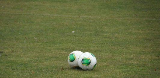 Medidas necessárias no futebol duas bolas de futebol juntas no meio de um gramado com linha
