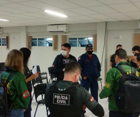 Polícia Civil faz buscas de provas em 12 municípios no caso dos respiradores superfaturados policiais homens e mulheres reunidos em pé em auditório usando uniformes da pc antes do início da operação
