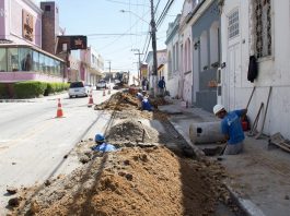 operários ao longo de buraco aberto em rua do centro histórico de são josé, carros desviando em meia pista
