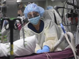 enfermeira usando equipamentos de proteção em todo o corpo faz massagem cardíaca em paciente em uti no meio de diversos aparelhos