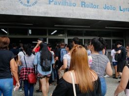 diversos jovens vistos de costas e em pé à espera de entrar em local para fazer prova do enem