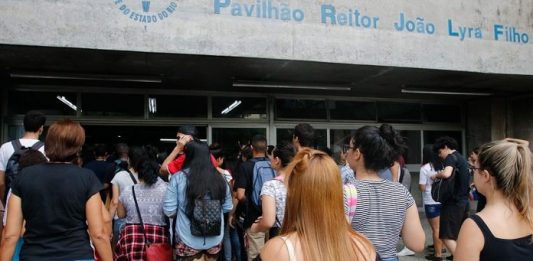 diversos jovens vistos de costas e em pé à espera de entrar em local para fazer prova do enem