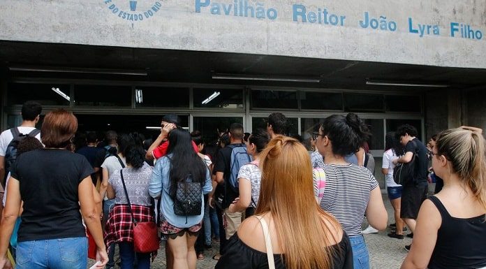 diversos jovens vistos de costas e em pé à espera de entrar em local para fazer prova do enem