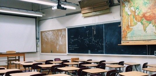 Justiça autoriza volta das aulas presenciais na educação básica em Florianópolis carteiras e mesas de madeira organizadas em sala de aula vazia com quadros negros ao fundo e mapas