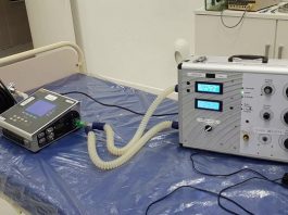 protótipo de respirador sobre mesa de hospital com outros equipamentos em volta