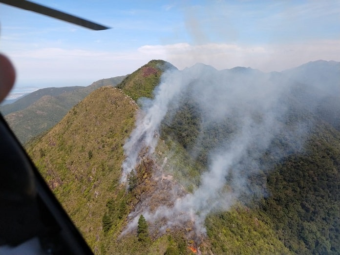 morro do cambirela com fumaça subindo de diversos pontos da vegetação em foto do helicóptero