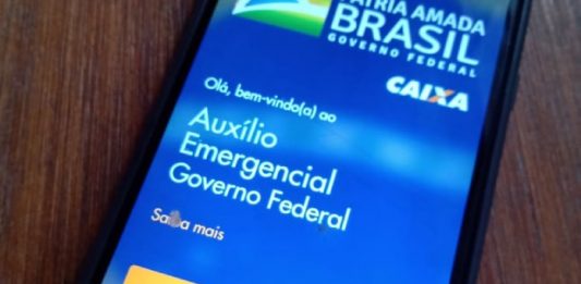 Mais de 8 mil servidores públicos municipais receberam auxílio emergencial em SC Auxílio Emergencial: Celular em cima da mesa com o aplicativo CAIXA Tem aberto.