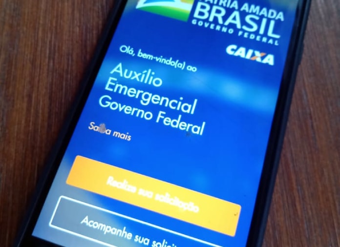 Auxílio Emergencial: Celular em cima da mesa com o aplicativo CAIXA Tem aberto.