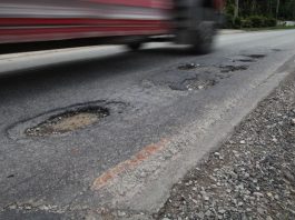 carro passando por estrada cheia de buracos
