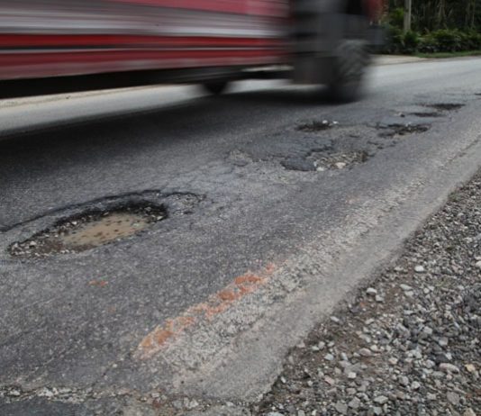 carro passando por estrada cheia de buracos