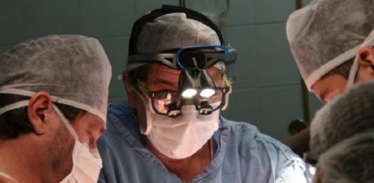 três médicos usando máscaras em sala de cirurgia