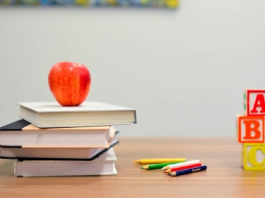 livros com uma maça e lápis emcima de mesa
