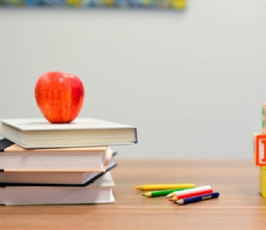livros com uma maça e lápis emcima de mesa