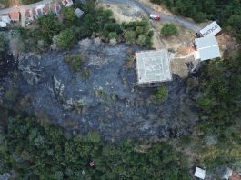 foto aérea mostra topo do morro queimado e casas ao redor