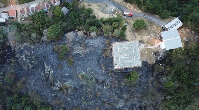 foto aérea mostra topo do morro queimado e casas ao redor