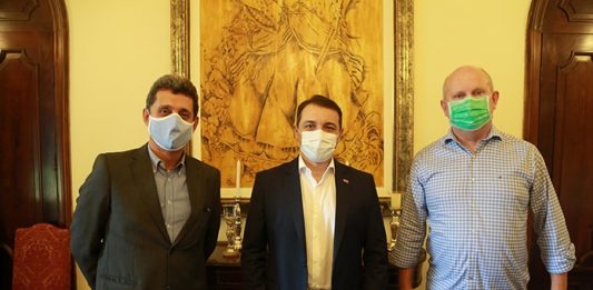 Tres homens de pé, usando máscaras, posando para a foto