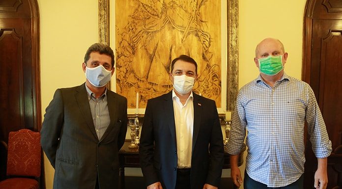 Tres homens de pé, usando máscaras, posando para a foto