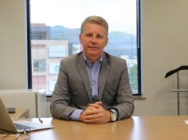 Amândio João da Silva Jr. em uma mesa de escritório com janela atrás