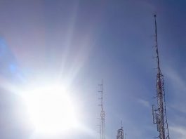 Visando o 5G, IMA lança a licença automática para antenas de telecomunicação diversas antenas vistas à contraluz do sol com equipamentos acoplados e no alto de um morro