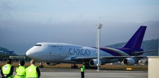 avião com inscrição "cargo" na lateral taxiando no aeroporto hercílio luz com funcionários de pista em primeiro plano