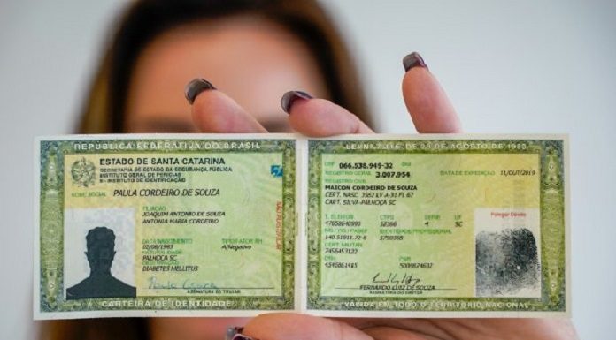mulher mostra para a foto modelo de carteira de identidade com nome social