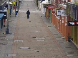 homem usando moletom e calça jeans é visto em imagem de camera de rua andando sozinho em calçadão com comércio em volta fechado no centro de florianópolis