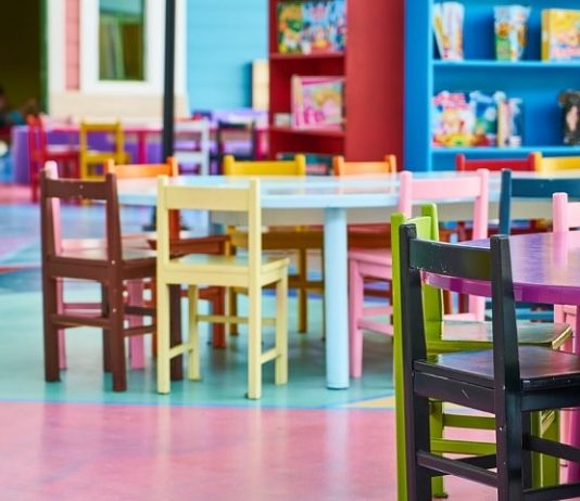 cadeirinhas coloridas de crianças organizadas ao redor de mezinhas em ambiente de creche