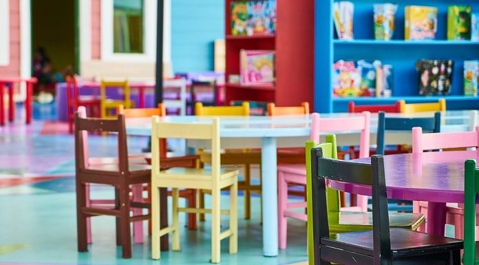 cadeirinhas coloridas de crianças organizadas ao redor de mezinhas em ambiente de creche