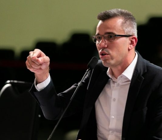 Na CPI, Zeferino e Borba acusam um ao outro sobre a compra de respiradores douglas borba fala ao microfone gesticulando; ele usa óculos e blazer; está em um auditório