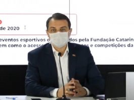 Moisés anuncia datas para volta de ônibus e aulas; decisão será de cada município governador moisés usa máscara falando em um microfone, sentado atrás de mesa e ao fundo painel com informações