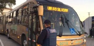 guarda de florianópolis em frente ao um ônibus bitrem da jotur
