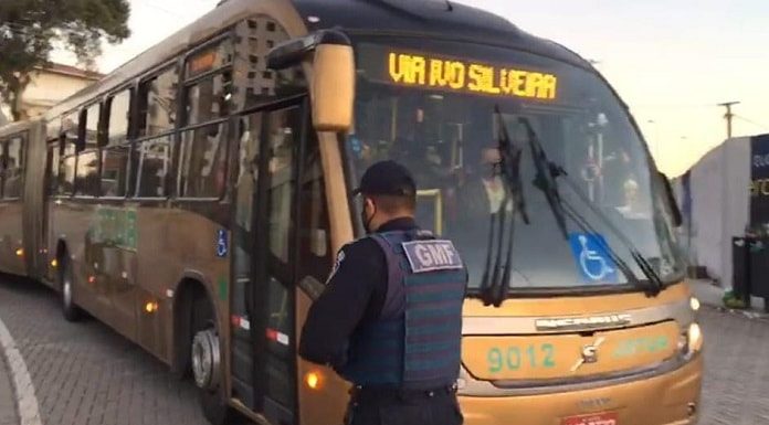 guarda de florianópolis em frente ao um ônibus bitrem da jotur