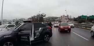 viatura creta da guarda de florianopolis atravessada na pista da ponte com carros passando ao lado em dia de chuva