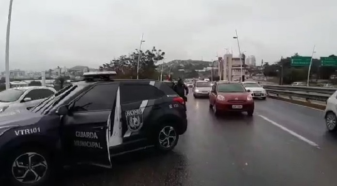 viatura creta da guarda de florianopolis atravessada na pista da ponte com carros passando ao lado em dia de chuva