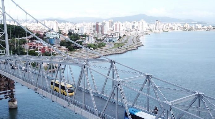 ônibus passando pela ponte hercílio luz vistos em foto aérea com bairro estreito ao fundo