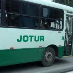 ônibus da empresa jotur visto de lado com logo em evidência no centro da foto