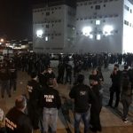 centenas de policias reunidos em pé em pequenos grupos em grande pátio com prédio ao fundo