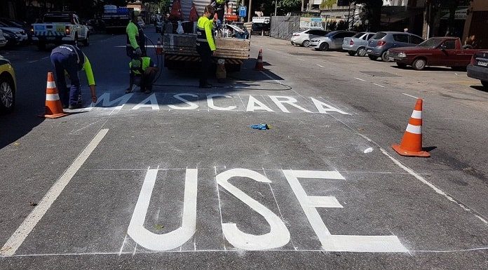 inscrição "máscara use" pintada como sinalização de trânsito no asfalto