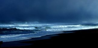 foto de uma praia no início da noite com mar agitado e muitas nuvens - previsão do tempo de chuva em sc