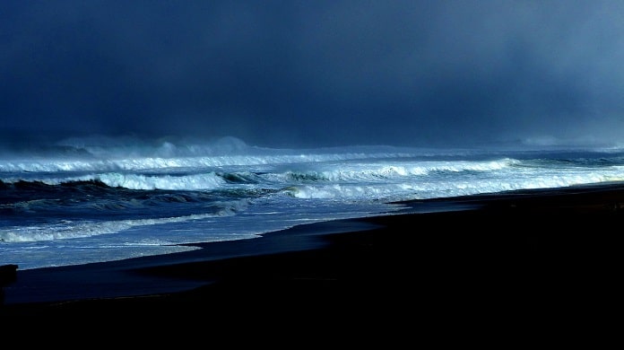 foto de uma praia no início da noite com mar agitado e muitas nuvens - previsão do tempo de chuva em sc