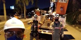 funcionário da celesc usando epi faz selfie com dois colegas posando atrás ao lado do caminhão
