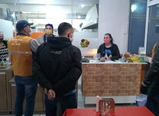 fiscal da vigilância sanitária conversando com dois homens e uma mulher